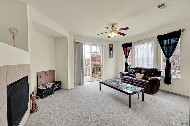 living room featuring light carpet, ceiling fan, and a fireplace