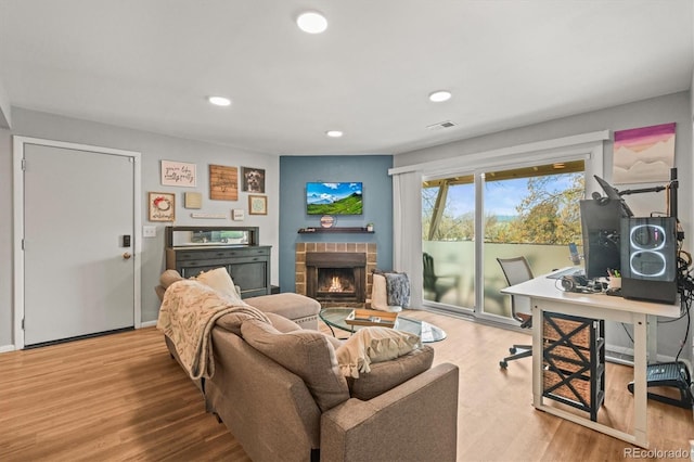 living area with recessed lighting, a brick fireplace, wood finished floors, and visible vents