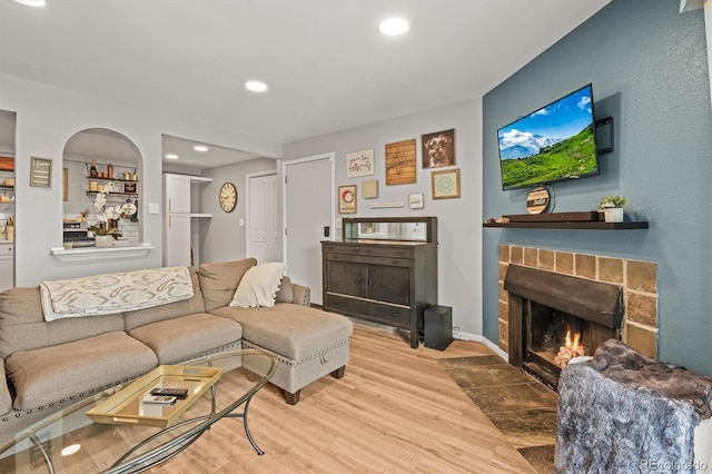 living area featuring a fireplace with flush hearth, wood finished floors, and recessed lighting