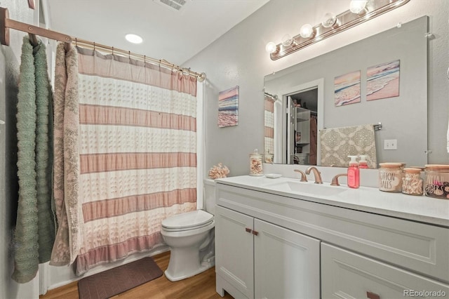 full bathroom featuring toilet, vanity, wood finished floors, and visible vents