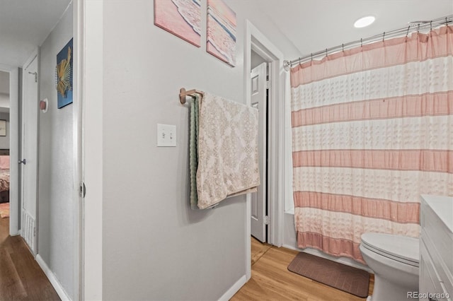 bathroom featuring toilet, a shower with shower curtain, wood finished floors, and baseboards