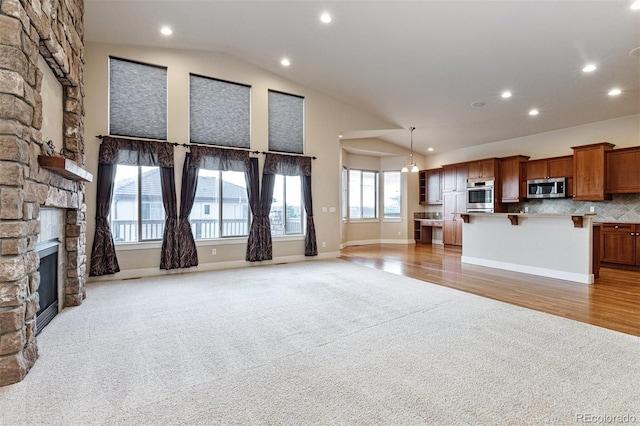 unfurnished living room with vaulted ceiling, light carpet, and a fireplace