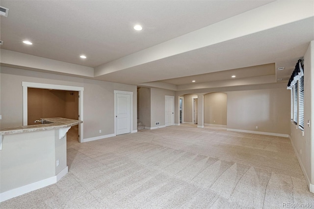 unfurnished living room featuring light colored carpet and a raised ceiling