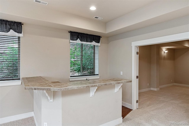 kitchen featuring carpet, kitchen peninsula, and a kitchen breakfast bar