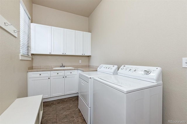 washroom featuring cabinets, separate washer and dryer, dark tile patterned floors, and sink