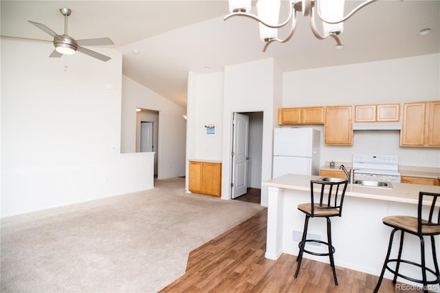 1766 Country Sun Dr, Windsor, CO 80550 - kitchen featuring white appliances, light countertops, a kitchen bar, light brown cabinets, and lofted ceiling