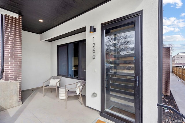 view of exterior entry with stucco siding and brick siding