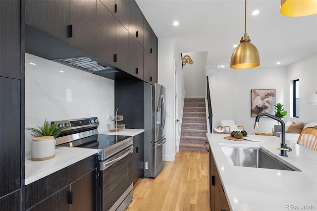 kitchen with appliances with stainless steel finishes, light wood-style floors, light countertops, and a sink