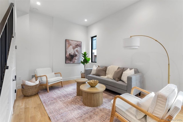 living room featuring baseboards, stairway, light wood-style flooring, and recessed lighting