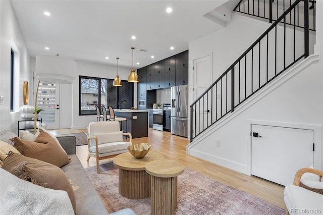 living area featuring light wood-type flooring, baseboards, stairway, and recessed lighting