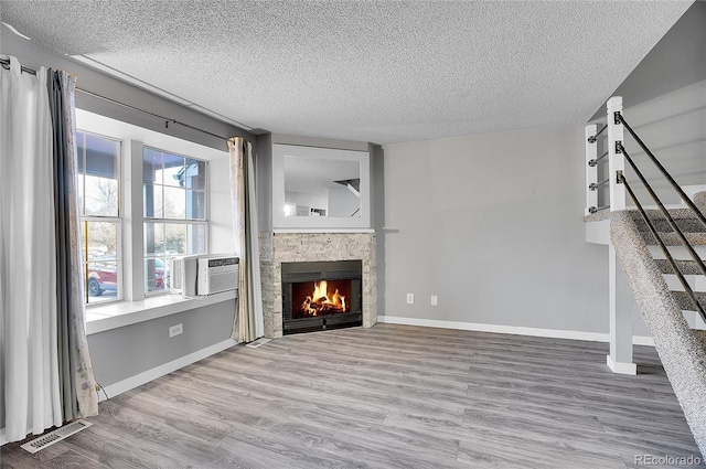 unfurnished living room with a fireplace, wood-type flooring, a textured ceiling, and cooling unit