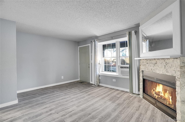 unfurnished living room featuring a fireplace, a textured ceiling, and light hardwood / wood-style flooring