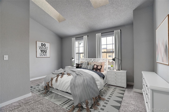 bedroom with light carpet, vaulted ceiling with skylight, and a textured ceiling