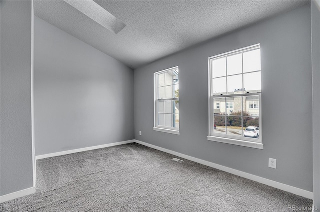 carpeted spare room featuring lofted ceiling and a textured ceiling