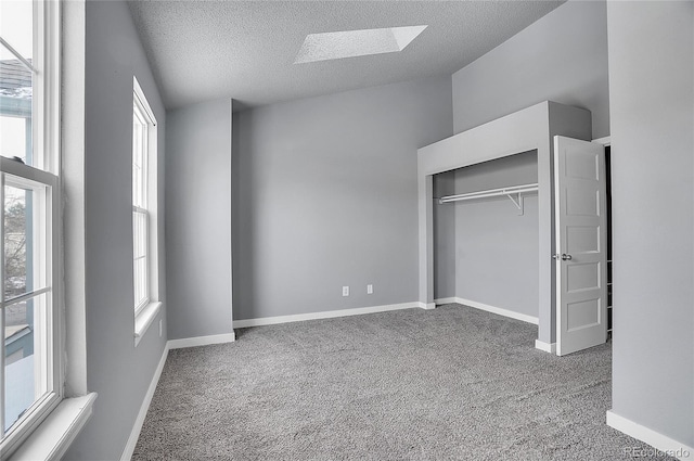 unfurnished bedroom with carpet floors, a textured ceiling, and a skylight