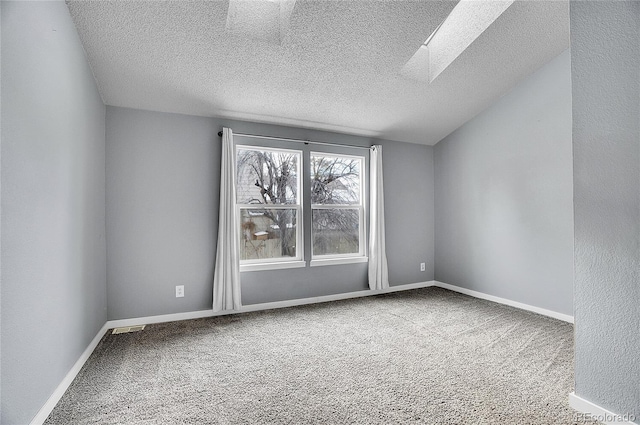 carpeted spare room featuring a textured ceiling and a skylight