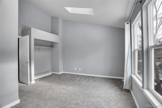 unfurnished bedroom with a skylight, carpet floors, and a textured ceiling