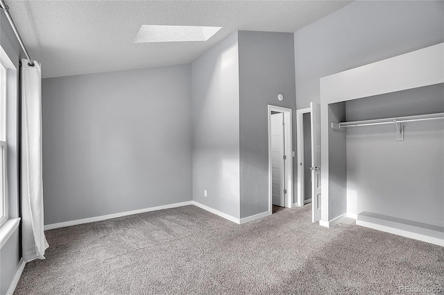 unfurnished bedroom with carpet flooring, a textured ceiling, a skylight, and a closet