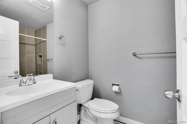 bathroom featuring vanity, a textured ceiling, and toilet