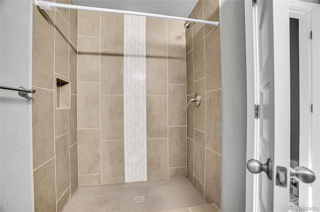 bathroom with a tile shower and a textured ceiling