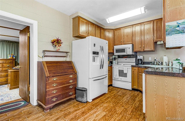 kitchen with hardwood / wood-style flooring, white appliances, and sink