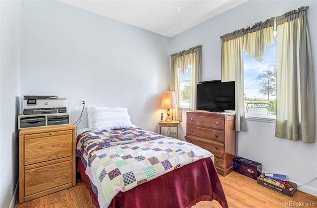 bedroom with multiple windows and light hardwood / wood-style flooring