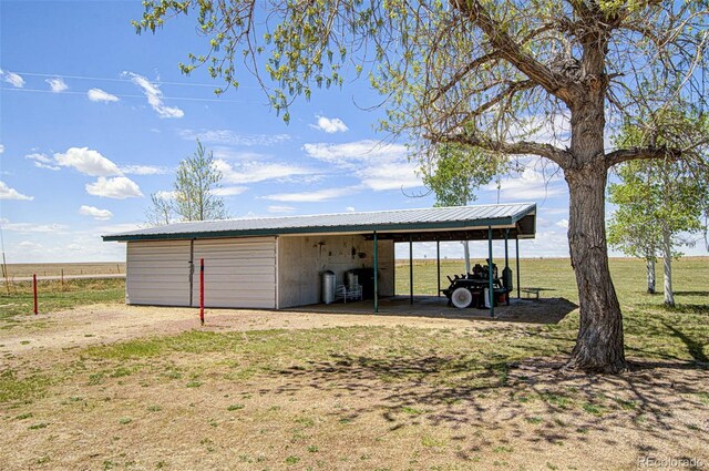 view of outbuilding featuring a rural view and a lawn