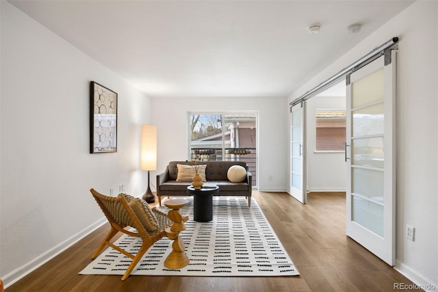 living area featuring a barn door, baseboards, and wood finished floors