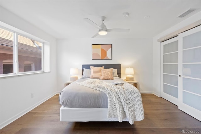 bedroom with a ceiling fan, wood finished floors, visible vents, and baseboards