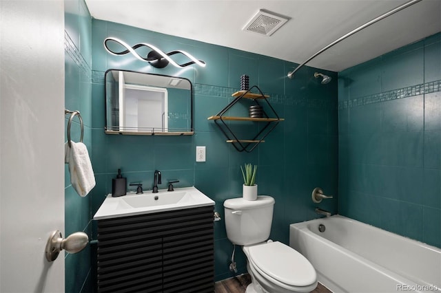 full bath with visible vents, toilet, vanity, tile walls, and  shower combination