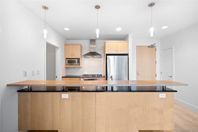 kitchen featuring stainless steel appliances, wall chimney exhaust hood, light brown cabinetry, light wood finished floors, and backsplash