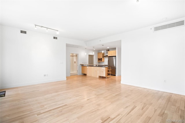 unfurnished living room featuring light wood finished floors and baseboards