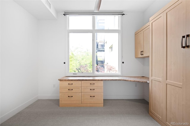 unfurnished office with built in desk and light colored carpet