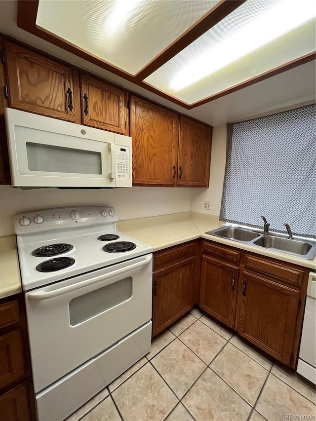 kitchen featuring sink, light tile patterned flooring, and white appliances