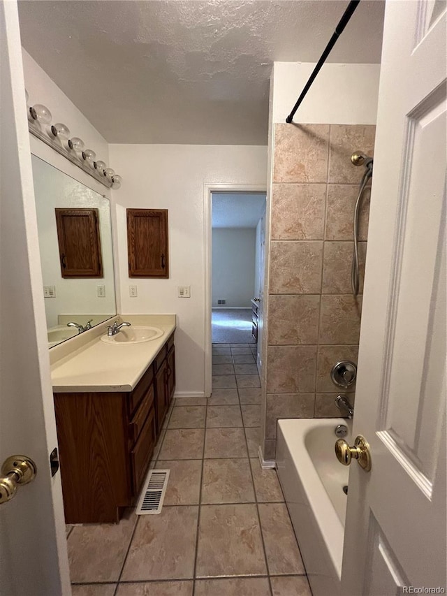 bathroom with tile patterned floors, vanity, a textured ceiling, and tiled shower / bath combo