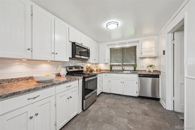 kitchen featuring appliances with stainless steel finishes, white cabinetry, tasteful backsplash, and a sink