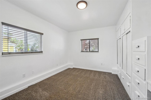 unfurnished bedroom featuring dark carpet and baseboards