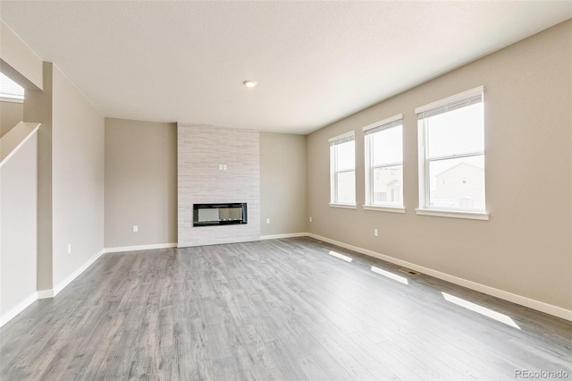 unfurnished living room featuring a large fireplace and wood-type flooring