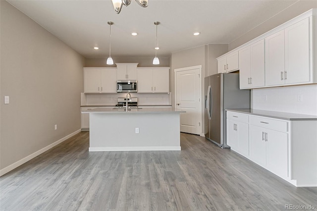 kitchen featuring pendant lighting, an island with sink, white cabinets, decorative backsplash, and stainless steel appliances