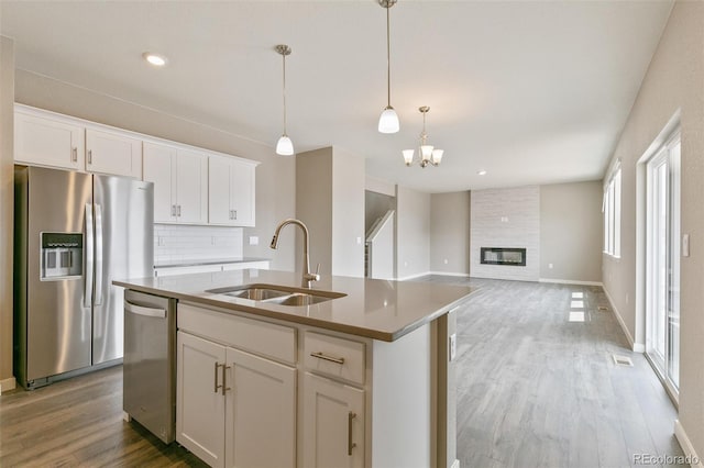 kitchen with a kitchen island with sink, sink, white cabinetry, and stainless steel appliances