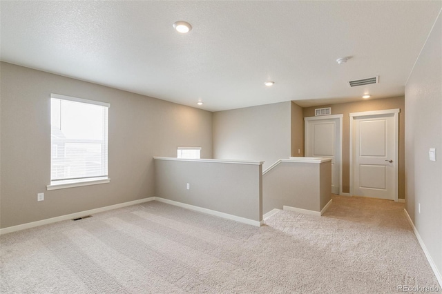 unfurnished room featuring light carpet and a textured ceiling