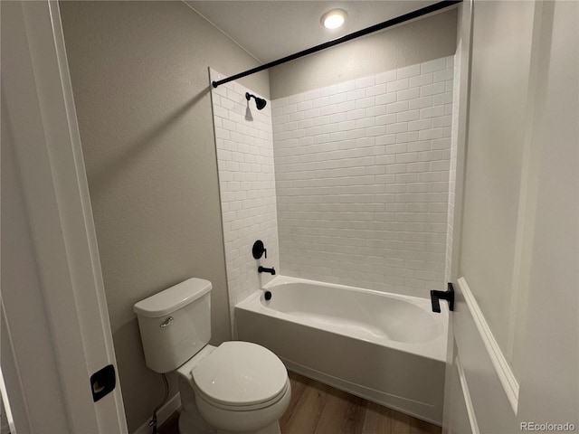 bathroom featuring shower / tub combination, toilet, wood finished floors, and a textured wall