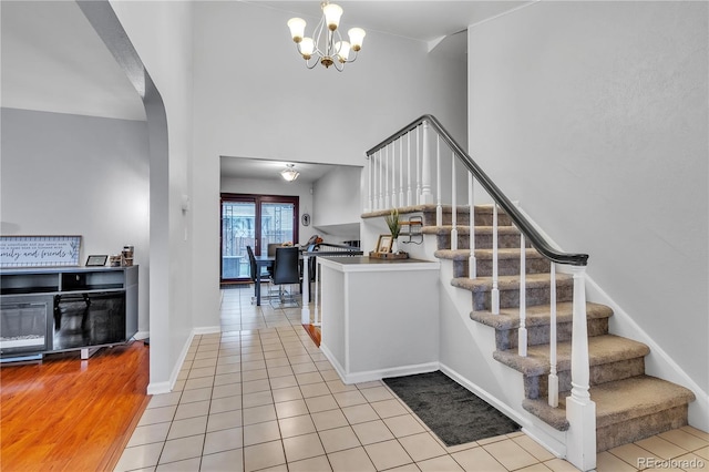 interior space featuring stairs, baseboards, a high ceiling, a chandelier, and arched walkways