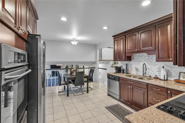 kitchen with backsplash, a sink, light stone counters, stainless steel appliances, and light tile patterned flooring