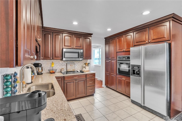 kitchen with light tile patterned flooring, light stone counters, a sink, decorative backsplash, and black appliances