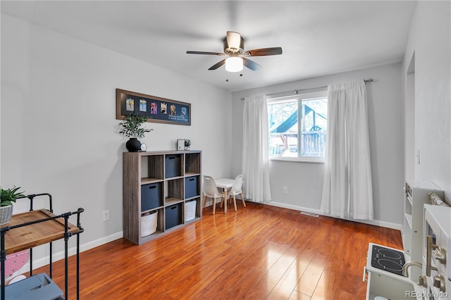 living area featuring baseboards, a ceiling fan, wood finished floors, and visible vents