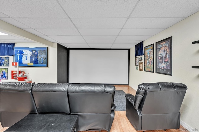 cinema featuring baseboards, wood finished floors, and a paneled ceiling
