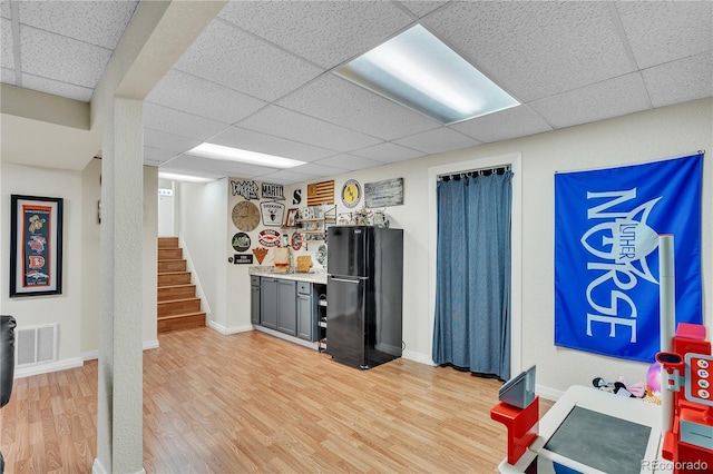 bar with a dry bar, freestanding refrigerator, a drop ceiling, and light wood-style flooring