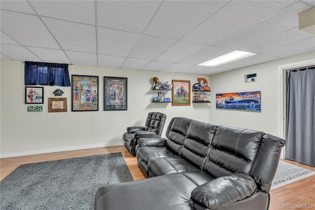 living room featuring baseboards, a paneled ceiling, and wood finished floors