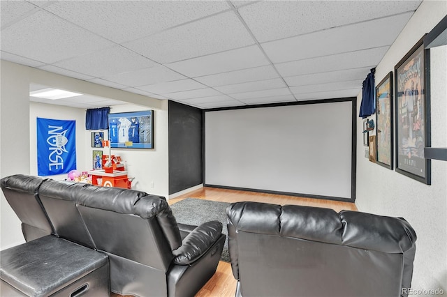 home theater room featuring baseboards, a drop ceiling, and wood finished floors